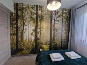 a bedroom with a wall mural of a forest at Tatra Apartments z zewnętrznym jacuzzi in Biały Dunajec