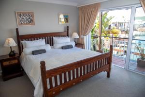 a bedroom with a large bed and a balcony at WATERFRONT 2 Bed Home with mooring at Knysna Quays in Knysna