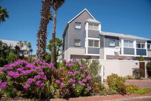 a house with purple flowers and palm trees at WATERFRONT 2 Bed Home with mooring at Knysna Quays in Knysna