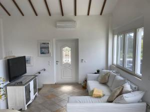 a living room with a white couch and a tv at Villa by the Lake in Karoubatika near Agios Ioannis in Agios Ioannis
