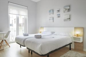 a white bedroom with a large bed and a window at Aiztondo - Basque Stay in San Sebastián