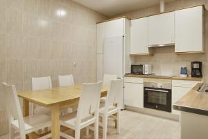 a kitchen with a wooden table and white cabinets at Aiztondo - Basque Stay in San Sebastián
