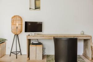 ein Wohnzimmer mit einem Schreibtisch, einem TV und einem Stuhl in der Unterkunft B&B Villa Tartine in Puurs