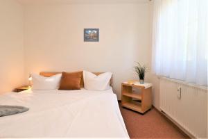 un dormitorio con una cama con sábanas y almohadas blancas en Altes Wasserwerk App 13, en Wustrow