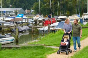 a man and woman walking down a path with a baby in a stroller at Siblu Camping Meerwijck in Kropswolde
