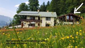 ein Haus auf einem Hügel mit einem Blumenfeld in der Unterkunft Ferienhaus hoch oben mit Alpen Panorama Königssee- Nichtraucherdomizil in Berchtesgaden