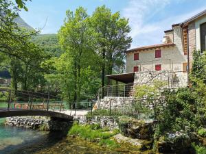 a bridge over a river in front of a building at Casa sul Fiume County House in Solagna