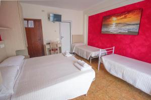una camera con due letti e una parete rossa di Hotel Maxim a Misano Adriatico