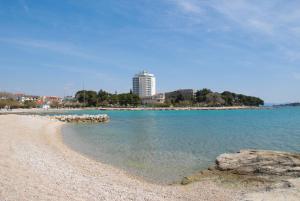een strand met rotsen in het water en een gebouw bij Villa Nonna in Vodice