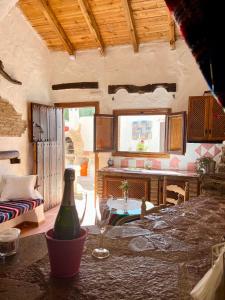 Cuevas de la Paz - Cave House Holidays في Los Carriones: غرفة معيشة مع طاولة وكأس للنبيذ