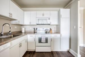a white kitchen with white cabinets and a sink at CozySuites 800 Tower 1BR w sky pool, gym! 16 in Louisville