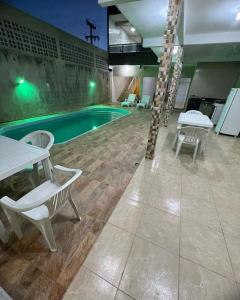 a pool with chairs and a table and a swimming pool at Pousada Águas de Peroba Flats e Suites in Maragogi