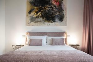 Un dormitorio con una cama con una pintura encima. en Lisetta Gardens Boutique & Suites, en Cisternino