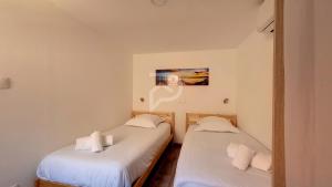 two twin beds in a room with white walls at Le Nature d'Eguisheim in Eguisheim