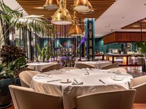 a restaurant with white tables and chairs and plants at Parque Santiago III Official in Playa de las Americas