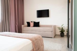 Habitación de hotel con sofá y TV en Lisetta Gardens Boutique & Suites, en Cisternino