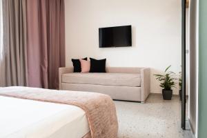 a hotel room with a couch and a tv at Lisetta Gardens Boutique & Suites in Cisternino
