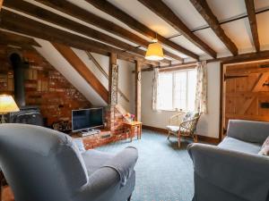 a living room with two chairs and a tv at 1 Forge Cottages in Saxmundham