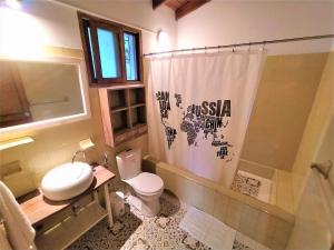 a bathroom with a toilet and a shower curtain at Finca Hostal Bolivar - Casa Quinta in Minca