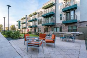 a patio with tables and chairs in front of a building at Modern 2BR CozySuites on Town Lake waterfront 03 in Tempe