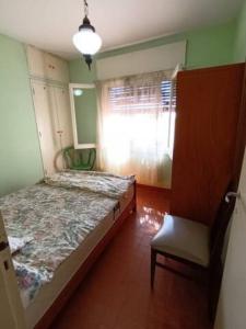 Un dormitorio con una cama, una silla y una ventana en Casa Rosa, en Alta Gracia