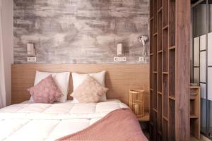 a bedroom with a bed with white sheets and pink pillows at INSPIRE Villages - Marennes Oléron in Marennes