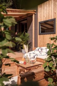 une terrasse en bois avec un canapé et une table dans l'établissement INSPIRE Villages - Marennes Oléron, à Marennes