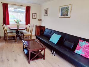 a living room with a black leather couch and a table at Sherlock's house - 4 spacious bedroom 8 beds Private parking & WIFI Accessibility Work & Family kids & pet welcome in Burton upon Trent