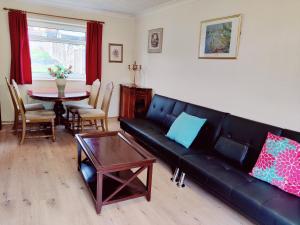 a living room with a black leather couch and a table at Sherlock's House-Melbourne 4 rooms 8 beds Free Private parking Free super Wifi Working facility 42" smart TV in Burton upon Trent