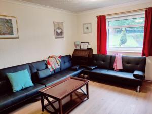 a living room with black leather couches and a table at Sherlock's house - 4 spacious bedroom 8 beds Private parking & WIFI Accessibility Work & Family kids & pet welcome in Burton upon Trent