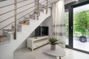 sala de estar con TV y escalera en Medusa Luxury Apartments en Néa Péramos
