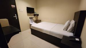 um pequeno quarto com uma cama e uma televisão em Green Glass Hotel em Calamba