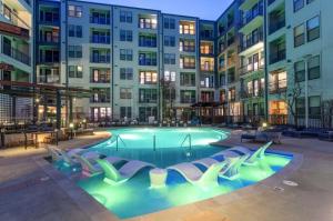 a swimming pool with chairs in front of a building at CozySuites Modern Midtown Condo 12 in Nashville