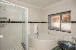 a white bathroom with a tub and a glass table at Millard Crescent Guest House in Port Elizabeth