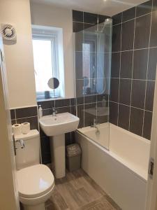 a bathroom with a toilet and a sink and a shower at Lovely Brand New 2 Bed House with Driveway Parking in Longford