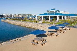 eine Gruppe Picknicktische mit Sonnenschirmen am Strand in der Unterkunft Friday Harbor Retreat Condo in Innisfil