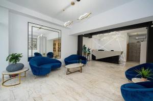 a living room with blue chairs and a piano at Signature PROMENADA Hotel Apartments in Mamaia Nord