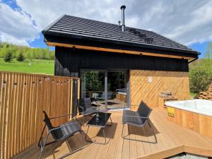 a small house with chairs and a tub on a deck at Projekt ŚWIT - domki z prywatną jacuzzi i sauną in Żywiec