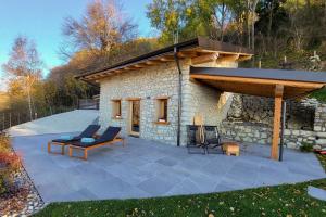 a stone house with a patio and a roof at Narciso Home in Adrara San Rocco
