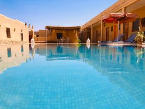 a swimming pool in front of a building at Riad Hotel Les Flamants in Merzouga