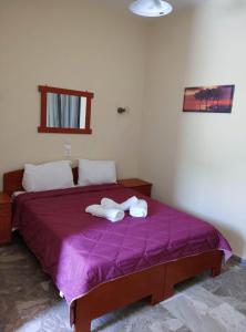 a bedroom with a purple bed with towels on it at Acrogiali Rooms in Riza