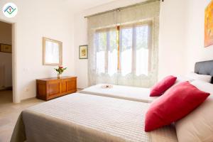 una camera da letto con un letto con cuscini rossi e una finestra di A Casa Di Rosa a Migliarino