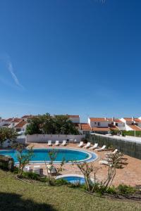 einen Pool mit Liegestühlen und das Meer im Hintergrund in der Unterkunft Bem Parece by Umbral in Albufeira