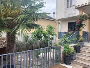 una recinzione di fronte a una casa con una palma di Appartement en zone pavillonnaire a Drancy