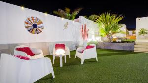 Eine Gruppe von Stühlen steht auf einem Rasen in der Unterkunft Villa Amatista Salinas Golf & Beach in Caleta de Fuste
