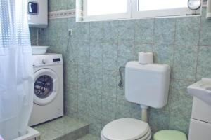 a bathroom with a toilet and a washing machine at TEODORA - kamenný domek 300 m od moře in Novalja