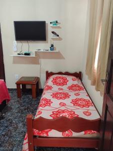 1 dormitorio con 1 cama y TV en la pared en kitnet A com piscina, en Arraial do Cabo