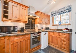 a kitchen with wooden cabinets and a stove top oven at Cove Cottage in Padstow