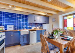a kitchen with blue cabinets and a table with chairs at Crown Mine Cottage in St. Just