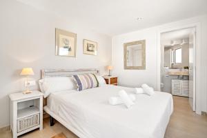 two beds in a white bedroom with two mirrors at Can Palanca in Cala Llonga